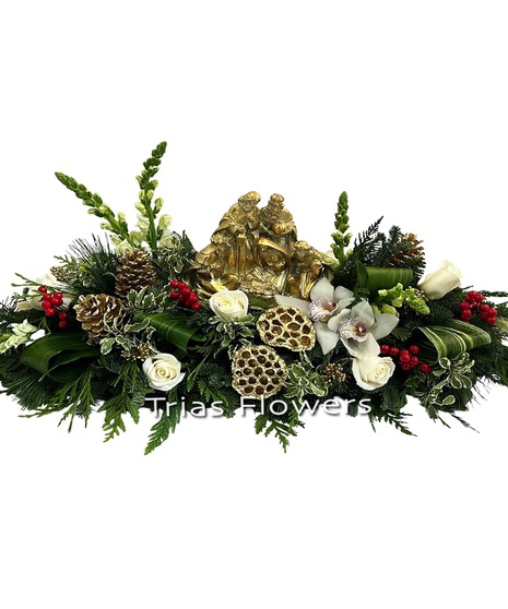 gold-toned christmas nativity scene surrounded by holiday flowers